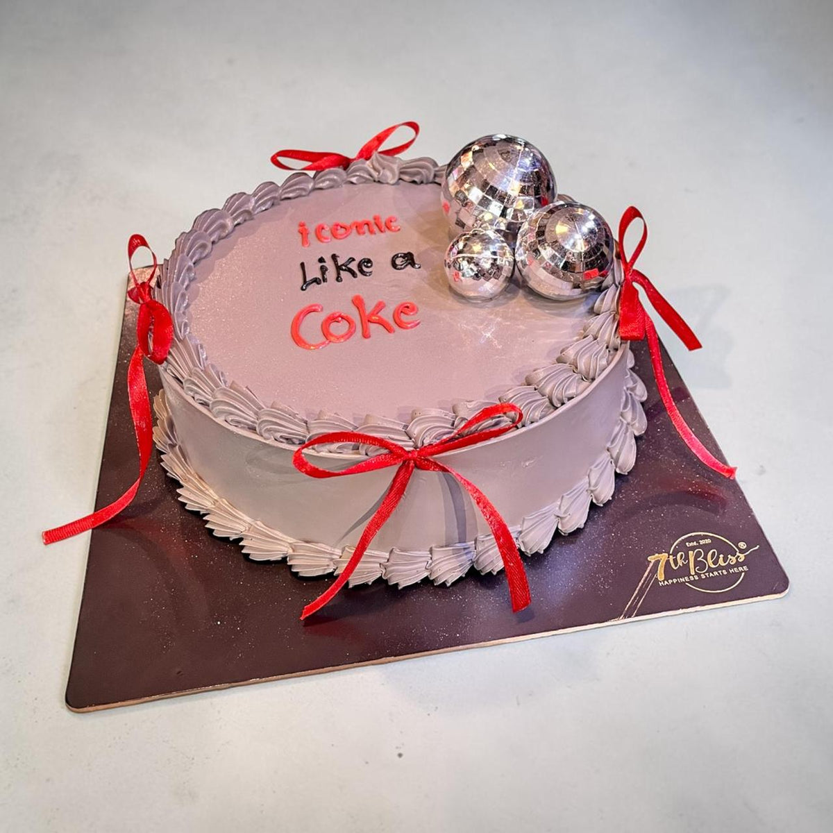 Eggless cream cake with red satin bows and silver disco balls, Coca-Cola theme, 7th Bliss Dwarka Delhi